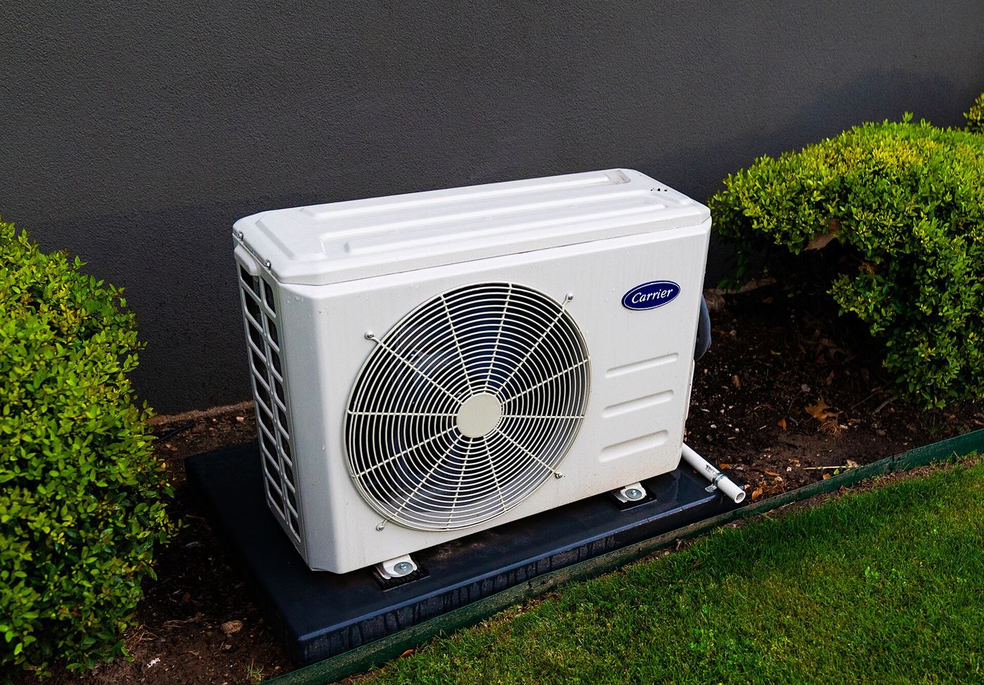 Outdoor heat pump and air conditioning condenser unit installed beside a residential home
